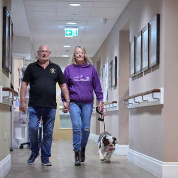 Residents walking down a corridor with their pet dog on a lead