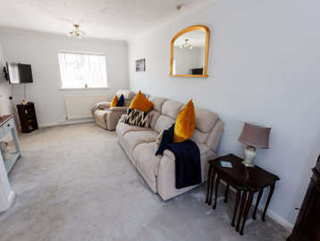 A lightly-decorated living room with window, sofa, TV and furniture