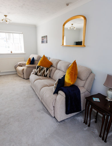 A lightly-decorated living room with window, sofa, TV and furniture 