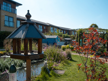 Garden area with a close-up photo of a bird table with pond behind