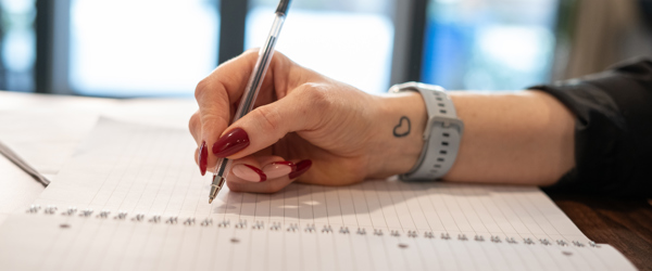 An employee uses a pen to write in a notebook