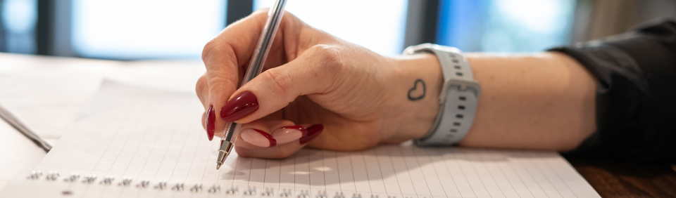 An employee uses a pen to write in a notebook 