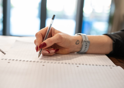 An employee uses a pen to write in a notebook
