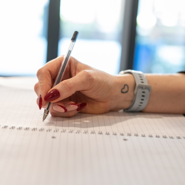 An employee uses a pen to write in a notebook