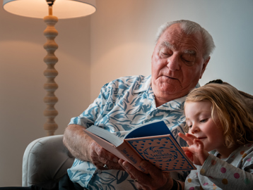 A resident reading a book with his granddaughter