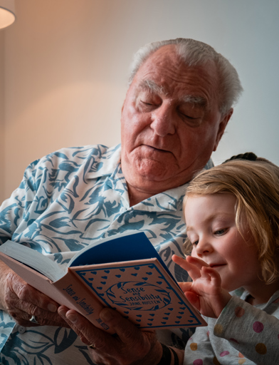A resident reading a book with his granddaughter