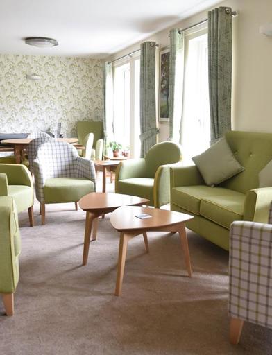 Resident's lounge area with soft armchair and sofa seating with tables 