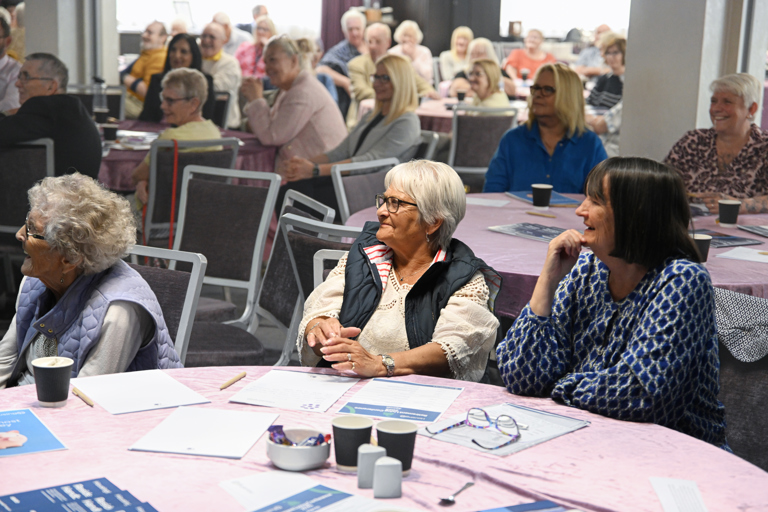 A table of residents listening to a speaker, all smiling and watching