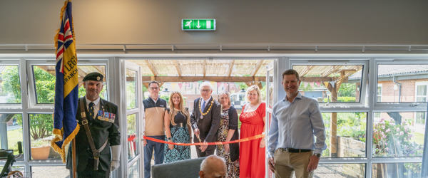 Housing 21 employees are joined by the Chairman of Sprowston Town Council and the standard bearer for the Catton Branch of the Royal British Legion to cut the ribbon Redmayne View following a makeover