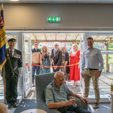 Housing 21 employees are joined by the Chairman of Sprowston Town Council and the standard bearer for the Catton Branch of the Royal British Legion to cut the ribbon Redmayne View following a makeover
