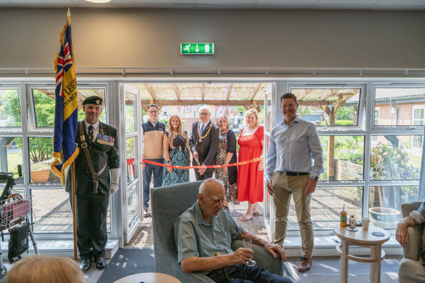 Housing 21 employees are joined by the Chairman of Sprowston Town Council and the standard bearer for the Catton Branch of the Royal British Legion to cut the ribbon Redmayne View following a makeover