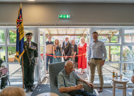 Housing 21 employees are joined by the Chairman of Sprowston Town Council and the standard bearer for the Catton Branch of the Royal British Legion to cut the ribbon Redmayne View following a makeover