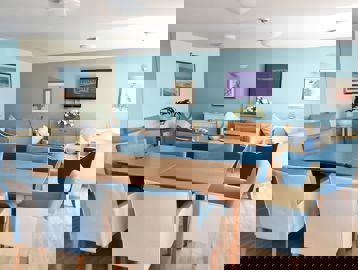 Communal lounge with soft seating, dining tables and TV at Alexandra Court