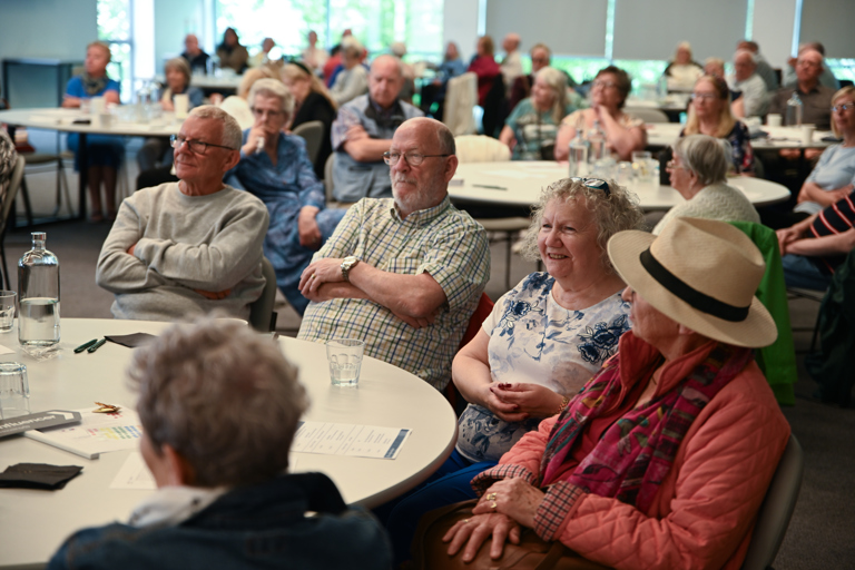 Residents at a table listening, smiling and laughing