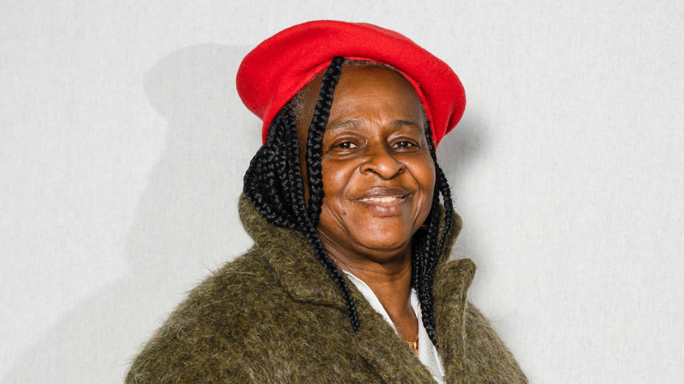 Extra Care resident wearing a red heat and a green coat looking to camera and smiling