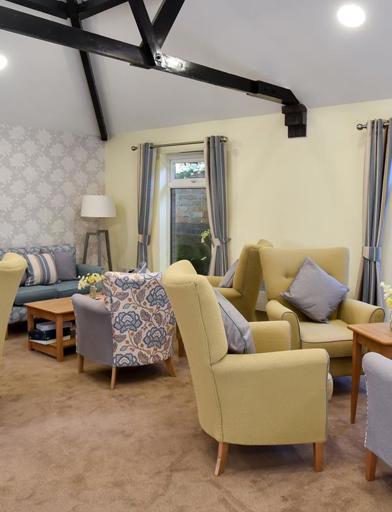 Residents' lounge with soft seating around a fireplace 