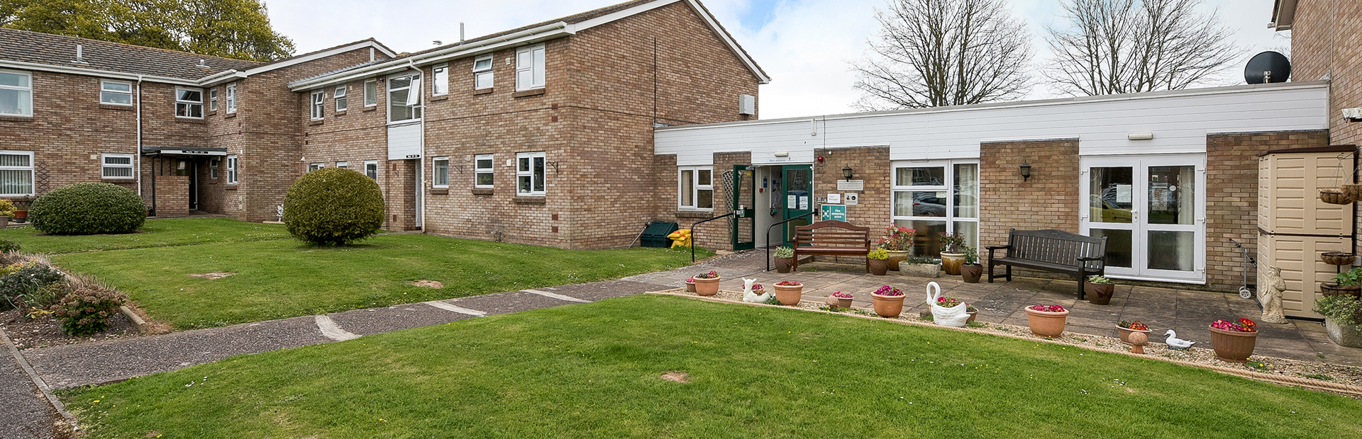 Front garden to the entrance of the scheme with plants and ornaments