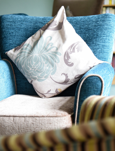 Close-up of a floral cushion on a blue and cream armchair in the communal lounge