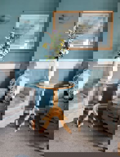 Two grey armchairs and coffee table with vase of flowers in communal area