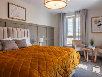Inside the show home apartment master bedroom with double bed, chairs and coffee table