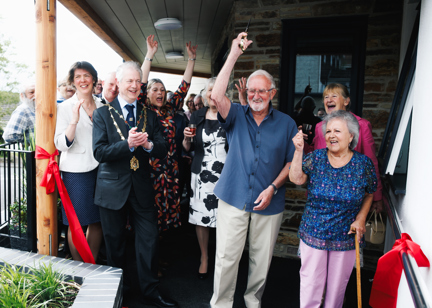 A group of residents, the Mayor, and other guests celebrate the ribbon cutting