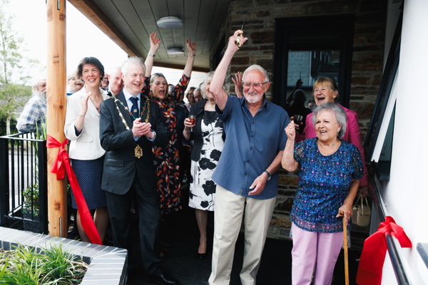 A group of residents, the Mayor, and other guests celebrate the ribbon cutting