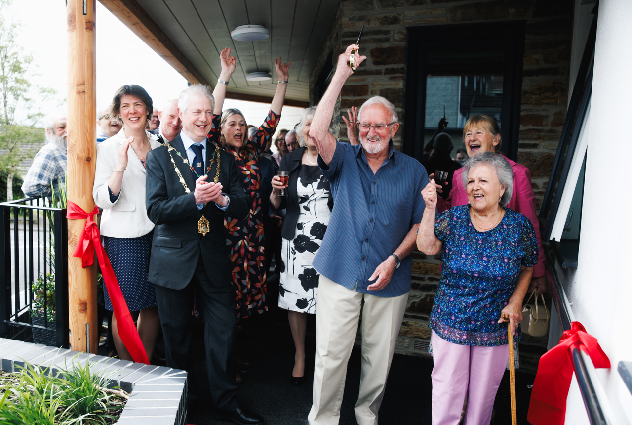 A group of residents, the Mayor, and other guests celebrate the ribbon cutting