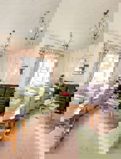 Residents' lounge with soft seating and tables 