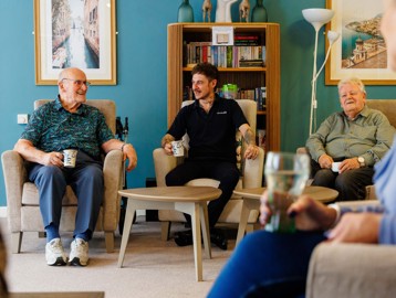 Two residents and a staff member talking in lounge area