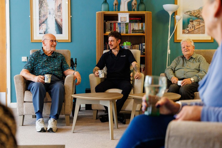 Two residents and a staff member talking in lounge area