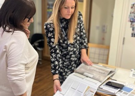 A lady shows another lady a series of kitchen brochures