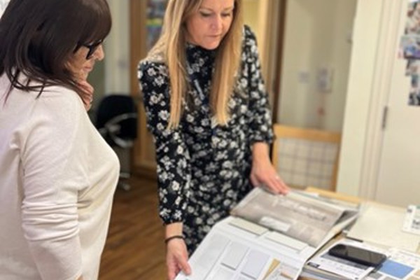 A lady shows another lady a series of kitchen brochures