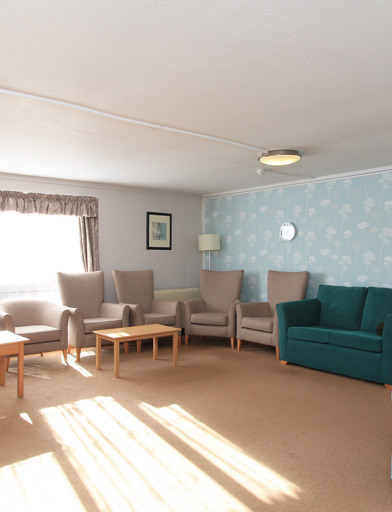 Residents' lounge with soft seating and coffee tables 