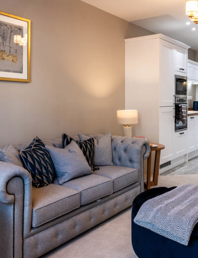 Inside the show home living area with large sofa and kitchen 