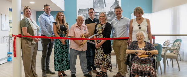Housing 21 resident Arnold cuts the ribbon at an open day at Green View surrounded by Housing 21 colleagues and residents 
