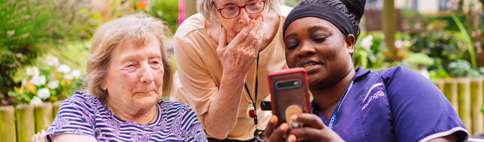 Residents and a Care Worker using a mobile phone 