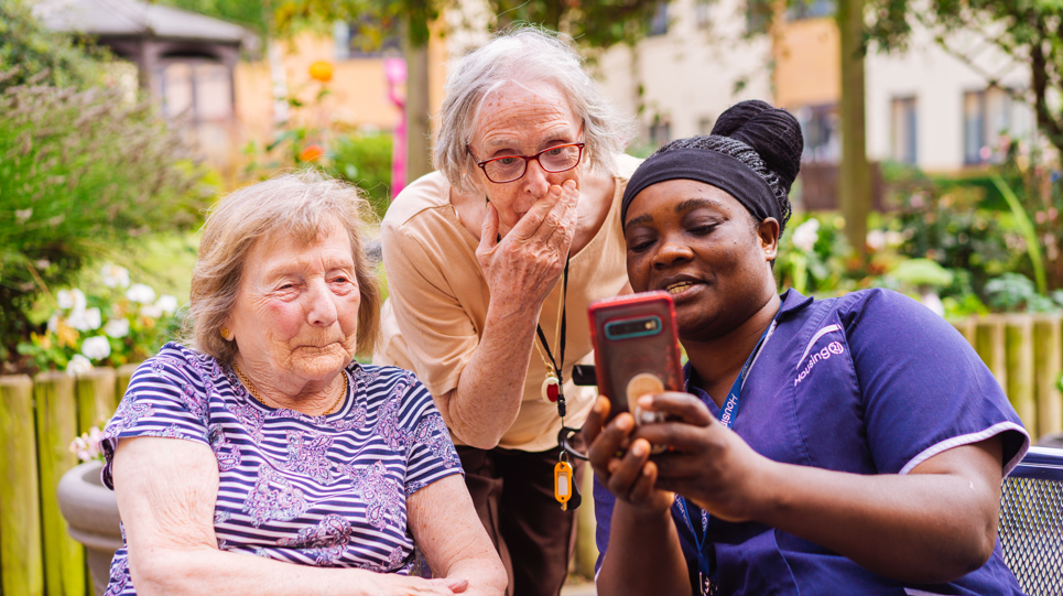 Residents and a Care Worker using a mobile phone