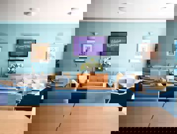 Residents lounge with seating, tables and TV at Alexandra Court