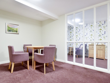 Communal area with tables and chairs alongside window at Acre Court