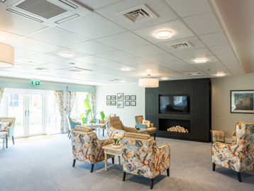 Communal residents' lounge with soft seating and wall-mounted TV