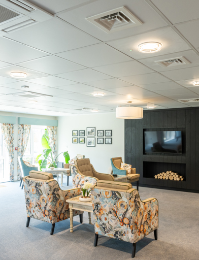 Communal residents' lounge with soft seating and wall-mounted TV 