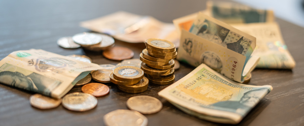 Money sits piled on a table comprising British coins and notes 