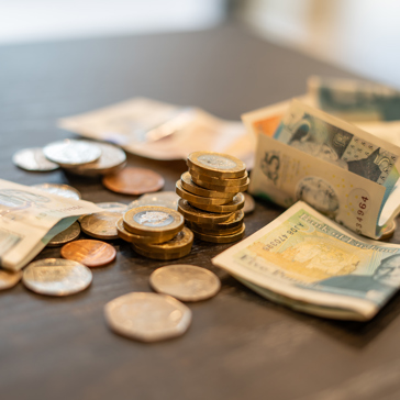 Money sits piled on a table comprising British coins and notes