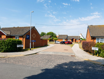The entrance to a cul-de-sac surrounded by bungalows set behind hedging 