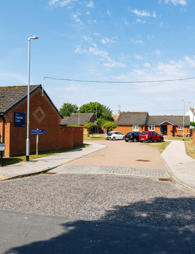The entrance to a cul-de-sac surrounded by bungalows set behind hedging  