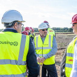 Employees and construction partners in high vis vests standing on land of a new development 