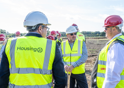 Employees and construction partners in high vis vests standing on land of a new development 