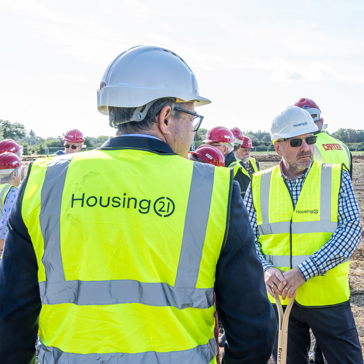 Employees and construction partners in high vis vests standing on land of a new development