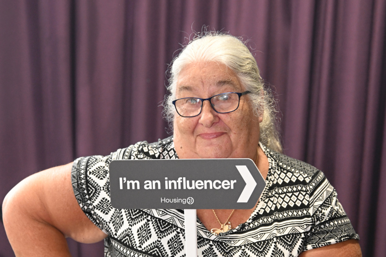 A resident holding the I’m an influencer sign and posing for the camera