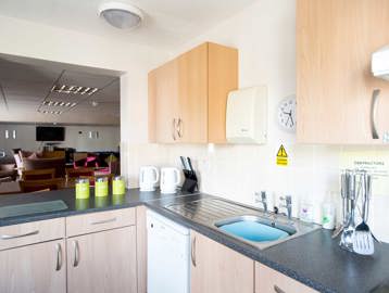 Communal resident's kitchen with open hatch looking into lounge area